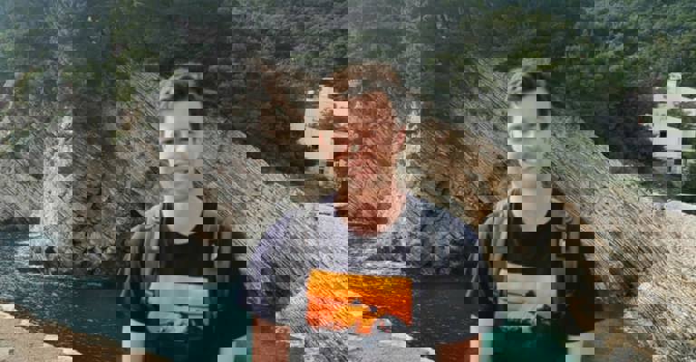 white man sat in front of a quarry and lake