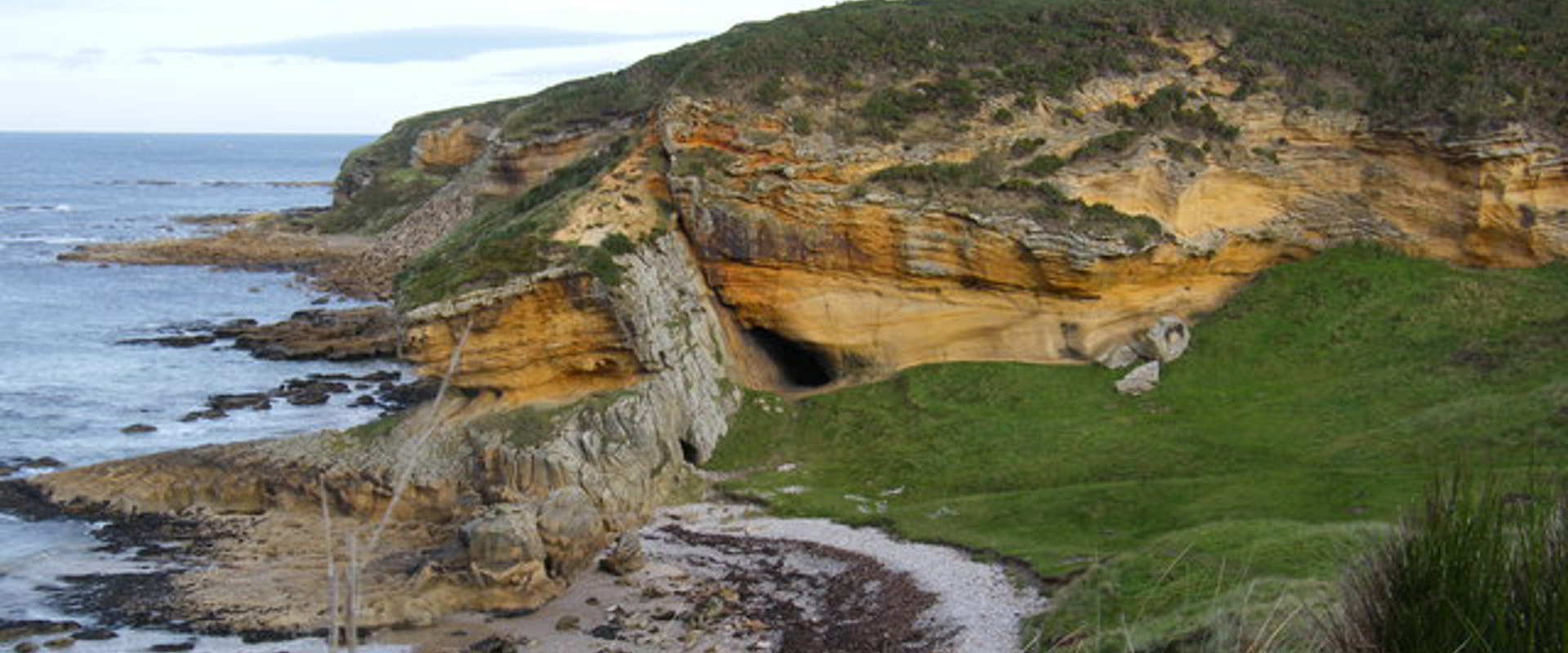 rocky cliff sloping down into the sea