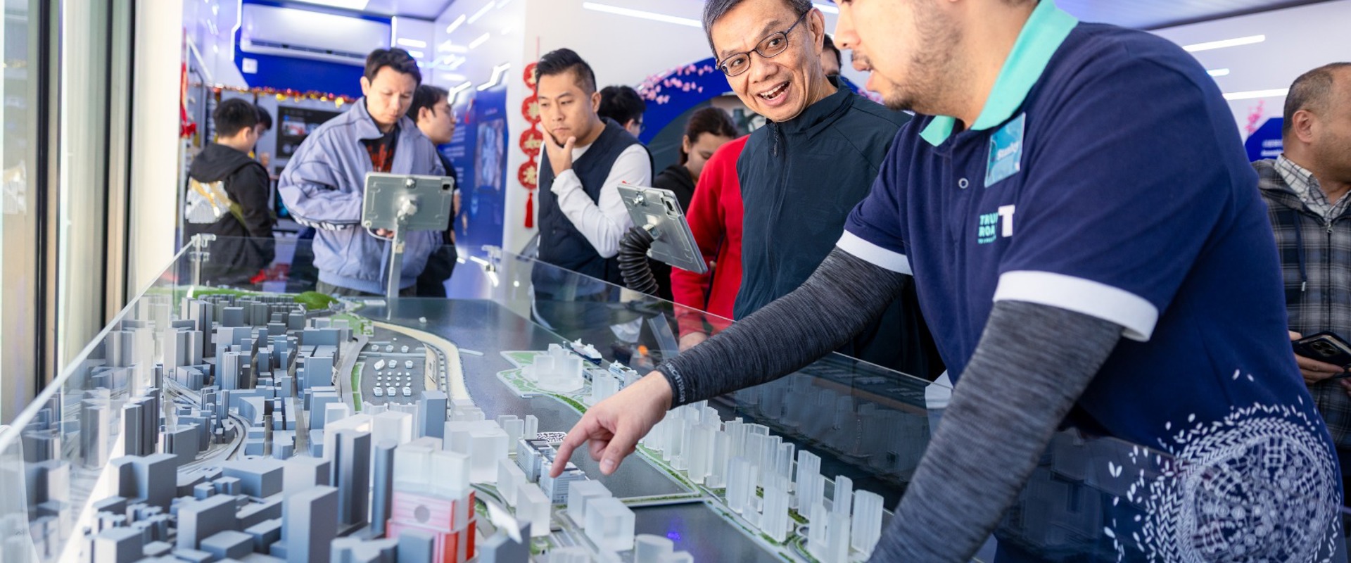 a group of people viewing a 3D map with a man explaining it to them