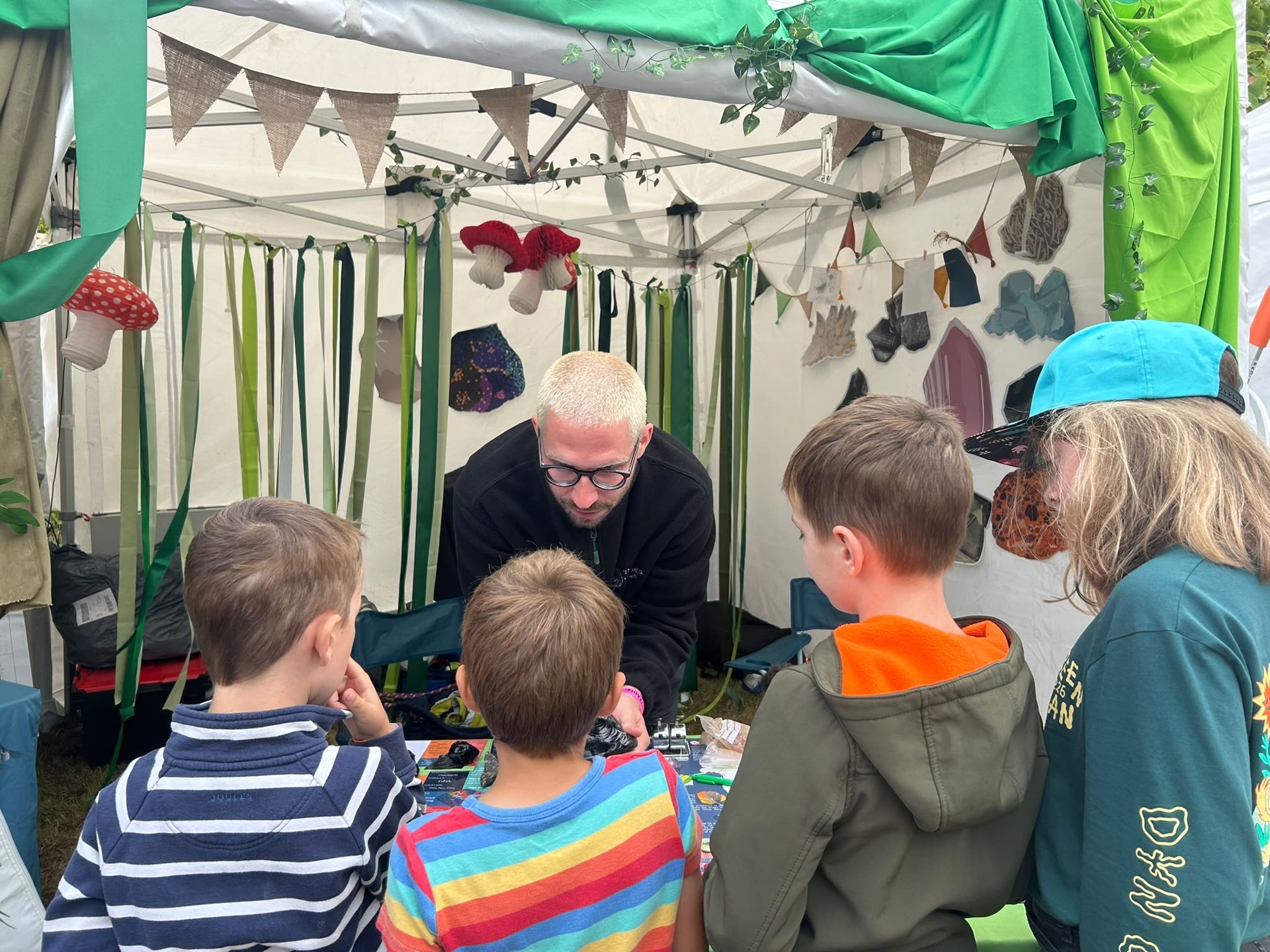 Four children interact with an a member of staff of the Geological Society during a geology outreach activity