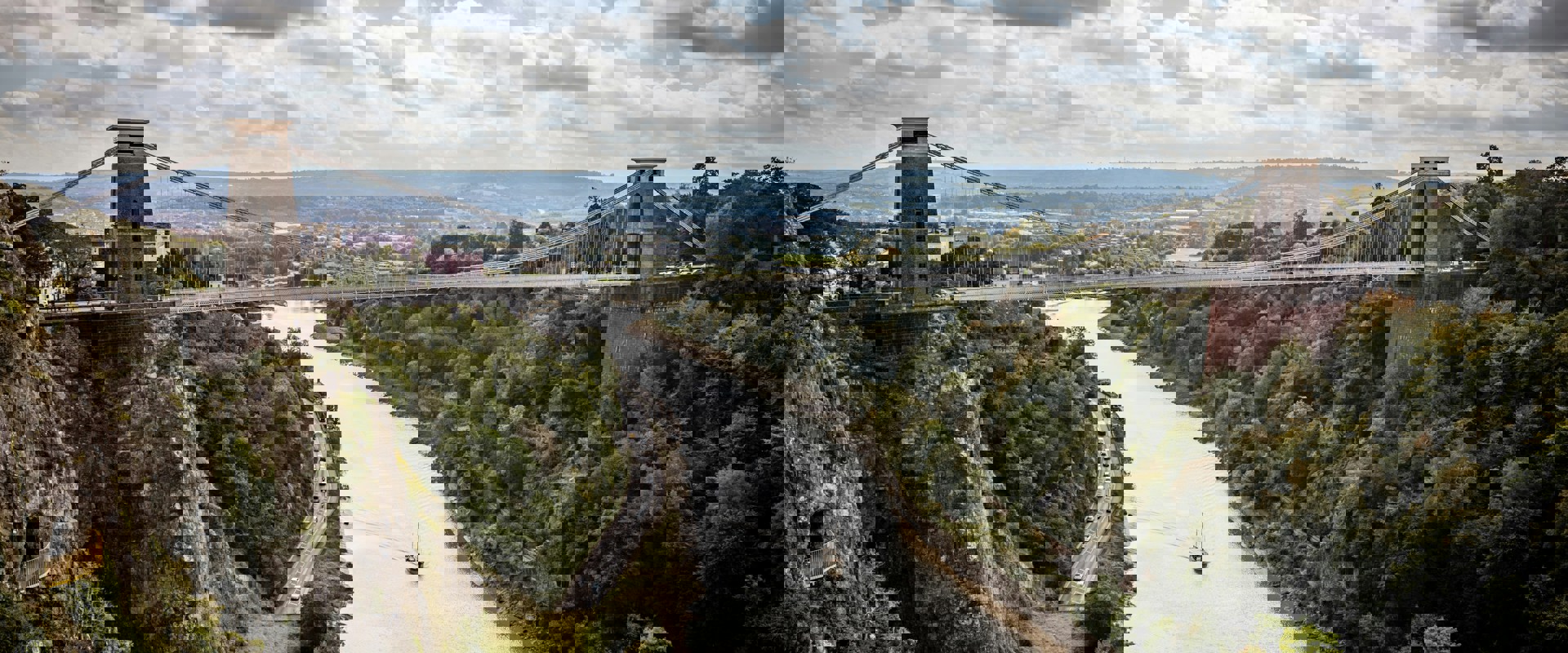 Clifton Suspension Bridge - a long bridge suspended over a river with trees either side