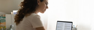 Woman on laptop with notepad studying