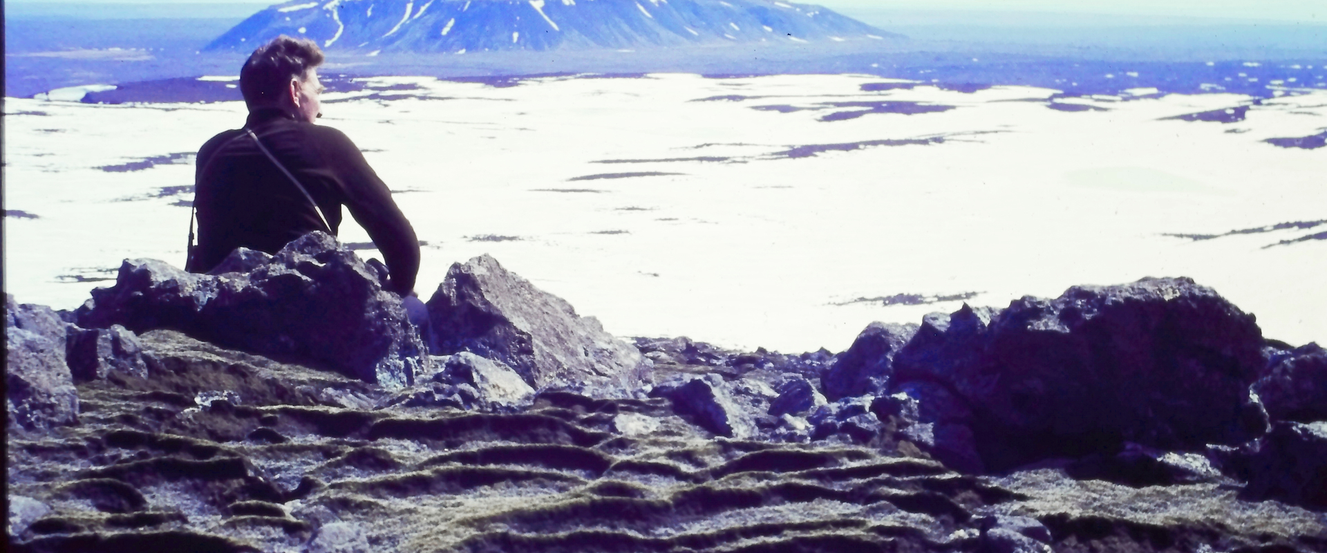 Icelandic Glaciological Society member, Árni Kjartansson, sits overlooking a glacier in Iceland.