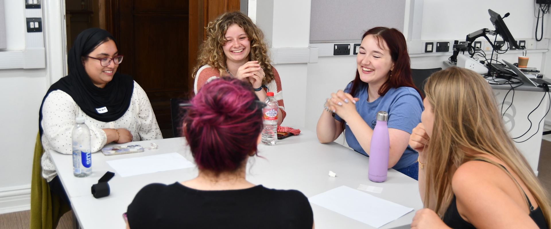 A group of four students chatting to each other con a classroom table