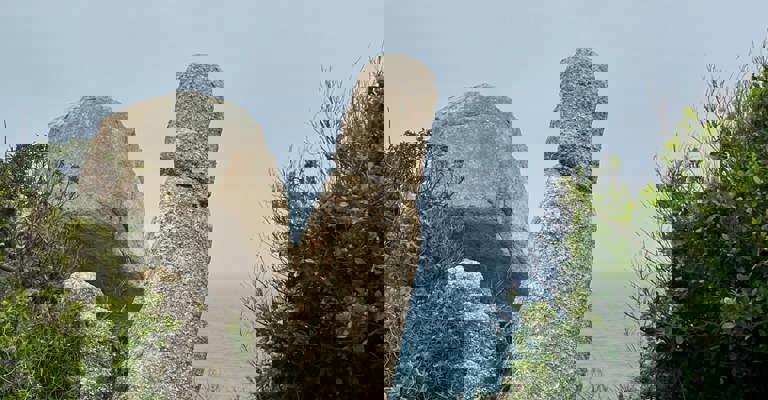 A tall rock with ocean in the background