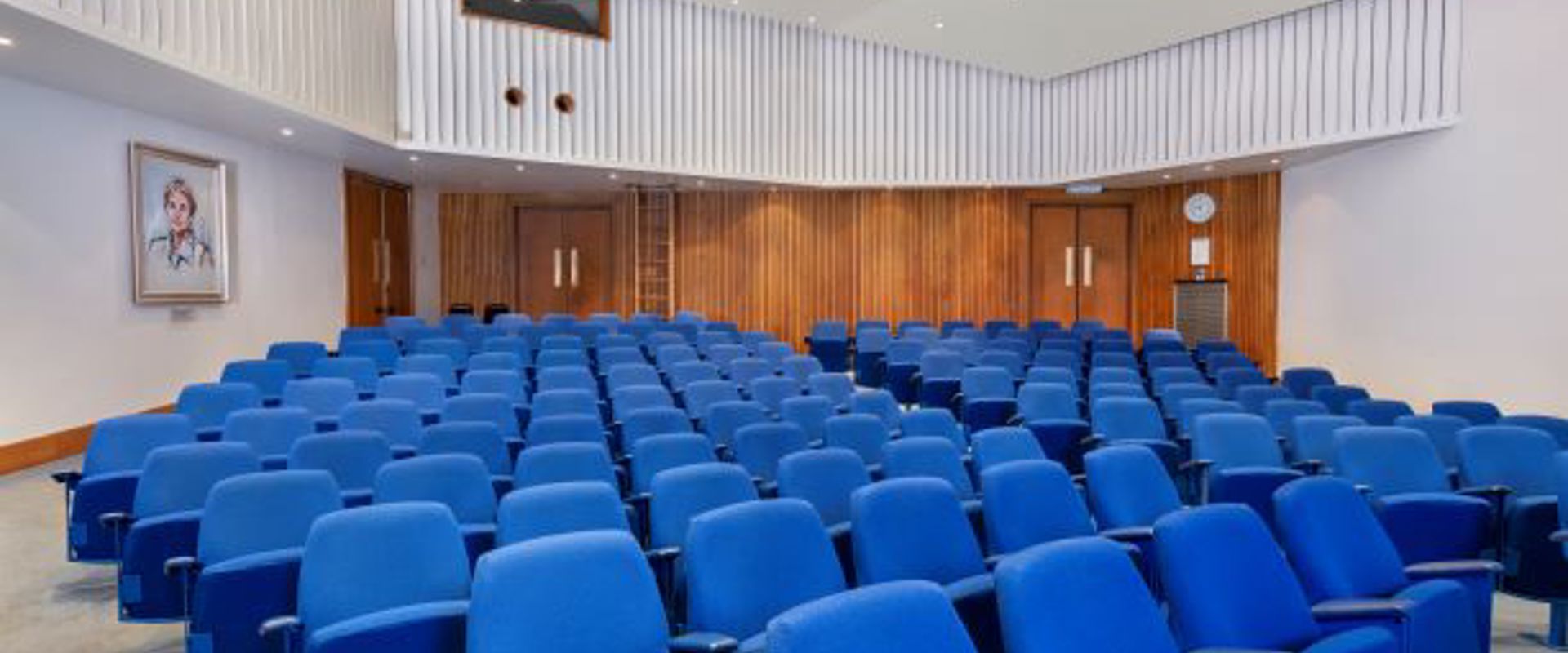rows of blue seating in a white room with wood panelling at the back