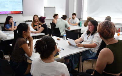 Students sitting in groups in a classroom environment chatting to each other