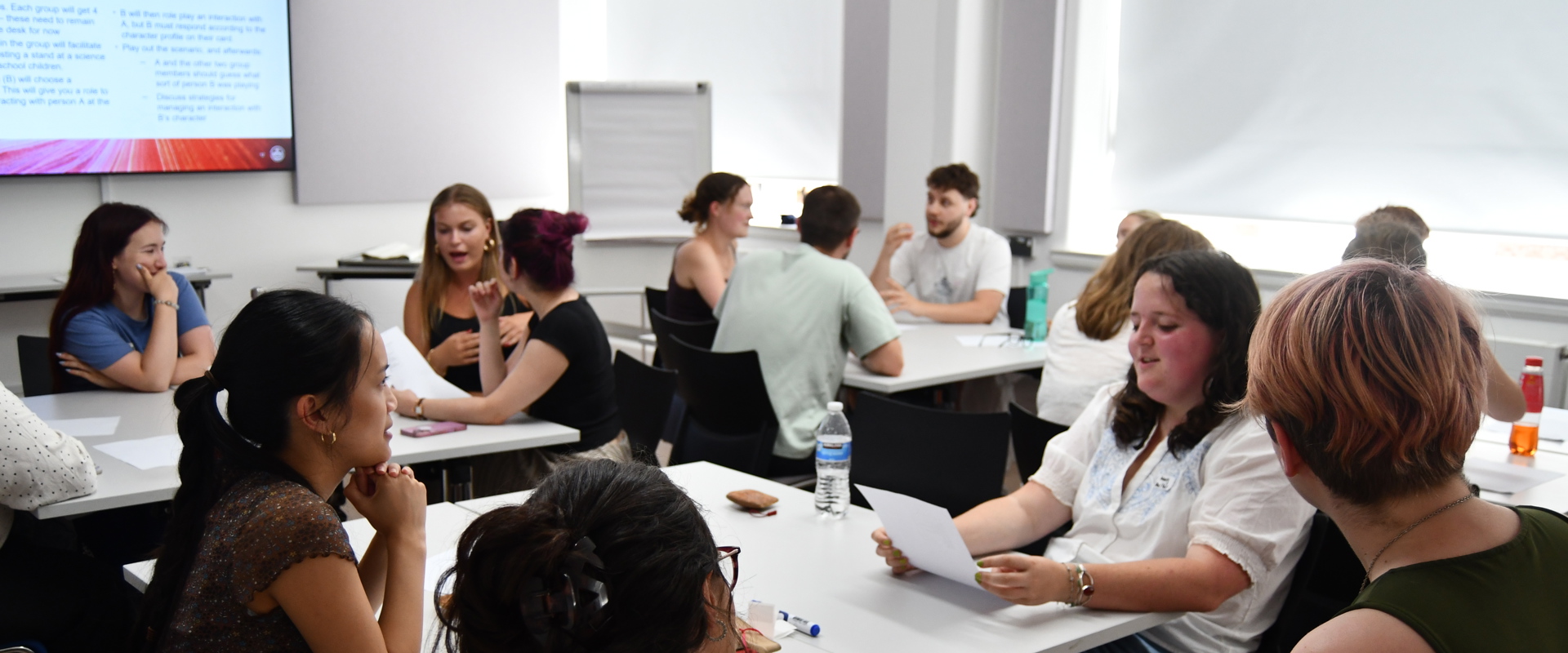 Students sitting in groups in a classroom environment chatting to each other