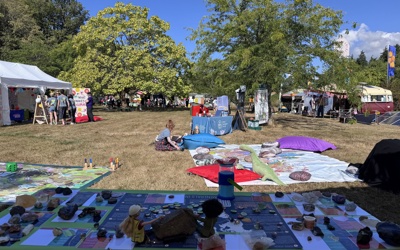 A table with minerls, informative posters and barbies in an open, green space during a festival