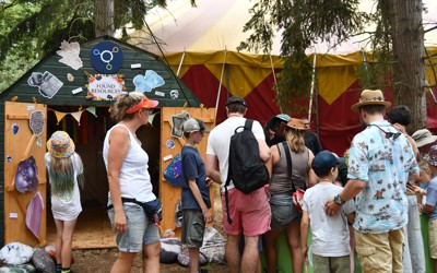 People of all ages gathered in front of minerals table standing next to a shed