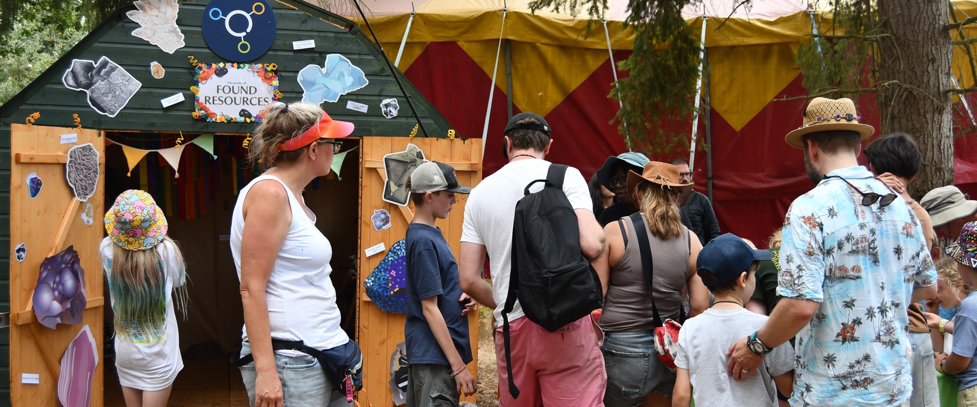 People of all ages gathered in front of minerals table standing next to a shed