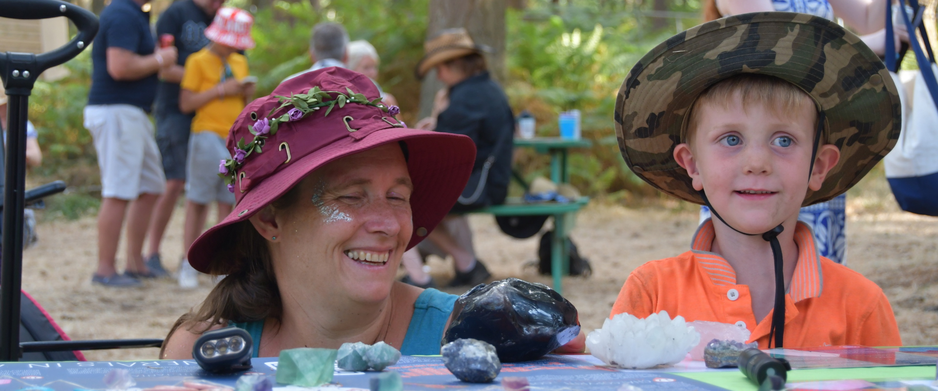 A mother and his son smiling in front a table filled with rocks and minarals