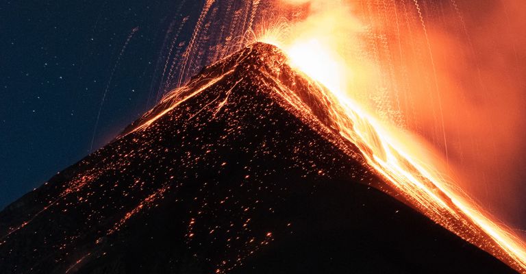 Erupting volcano at night with red lava and fire