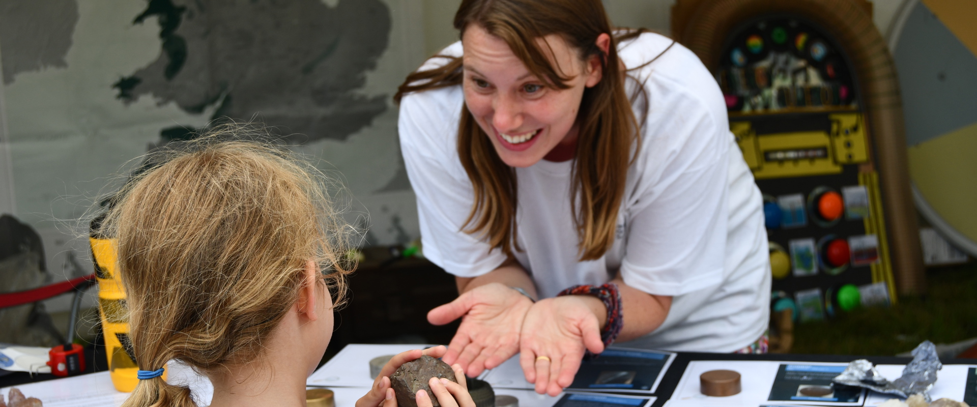 Science educator enthusiastically showing a mineral to a child e
