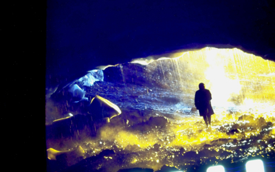 A silhouetted person stands beneath the vaulted ceiling of a glacial cave in Iceland. 
