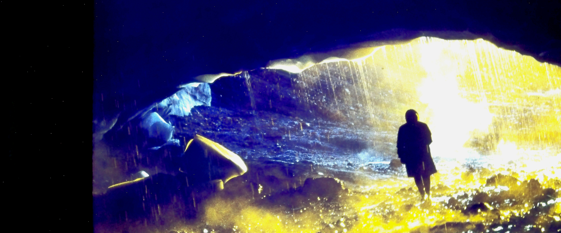 A silhouetted person stands beneath the vaulted ceiling of a glacial cave in Iceland. 