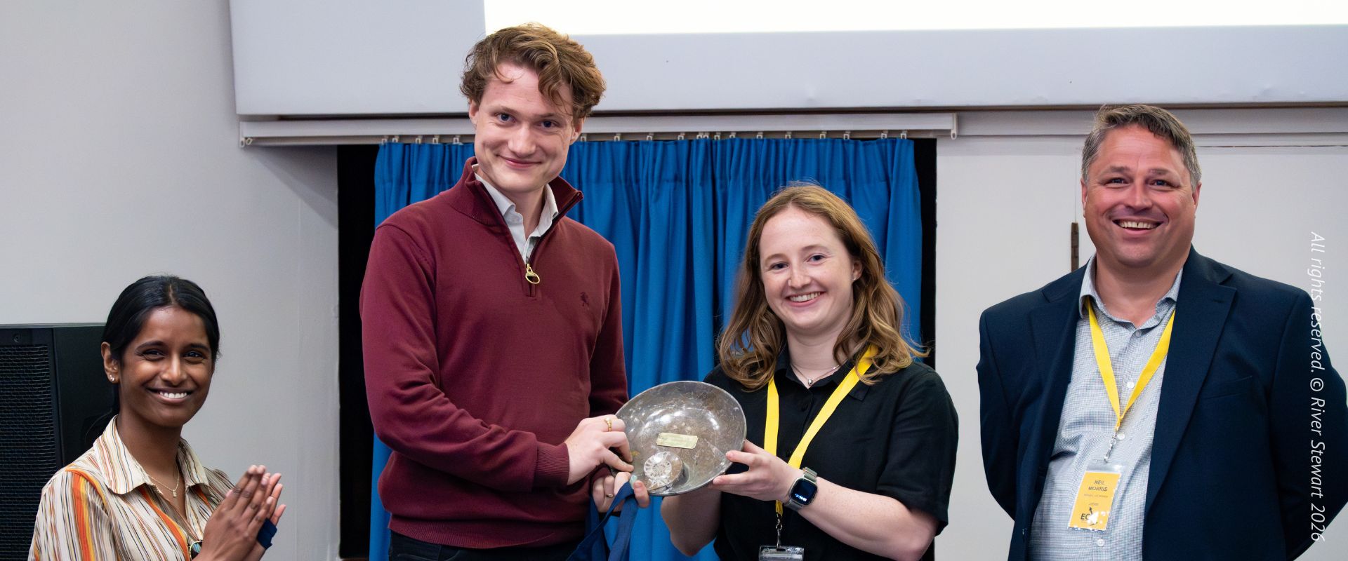 Award winner poses for photo with trophy in hand next to peers