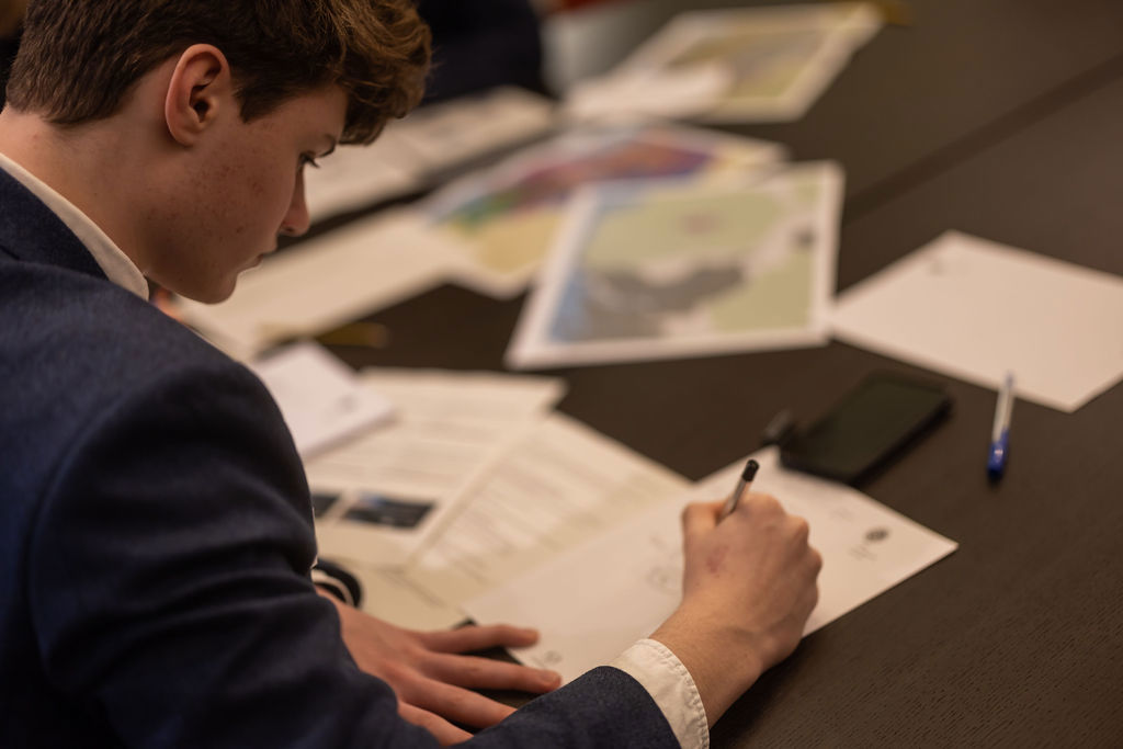 A secondary student writes on worksheets including geological maps