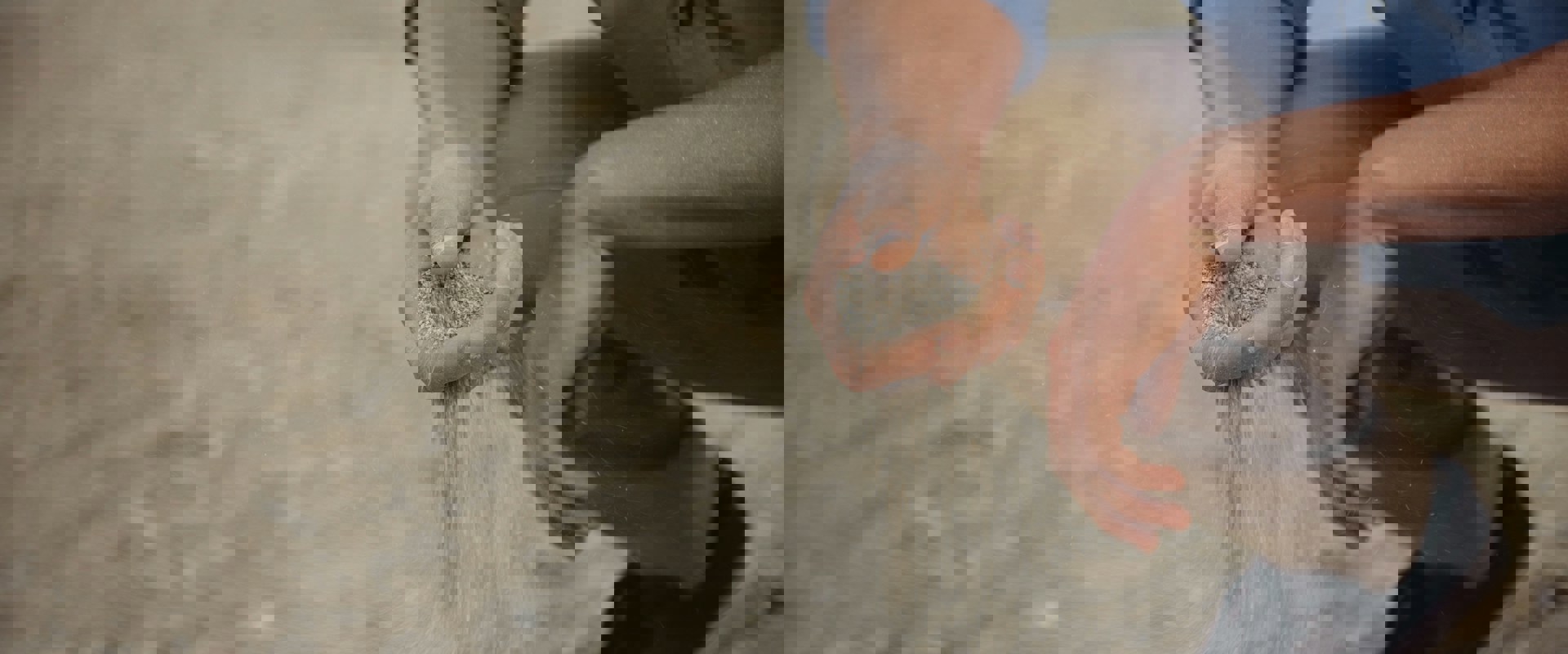 person crouching with sand falling through their fingers