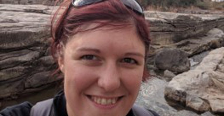 white woman with red hair and sunglasses on her head