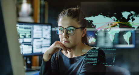 young woman with glasses looking at a screen with computer monitor in the background