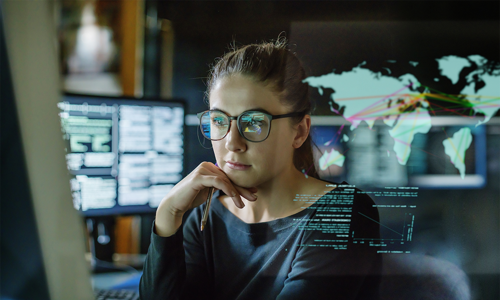 young woman with glasses looking at a screen with computer monitor in the background