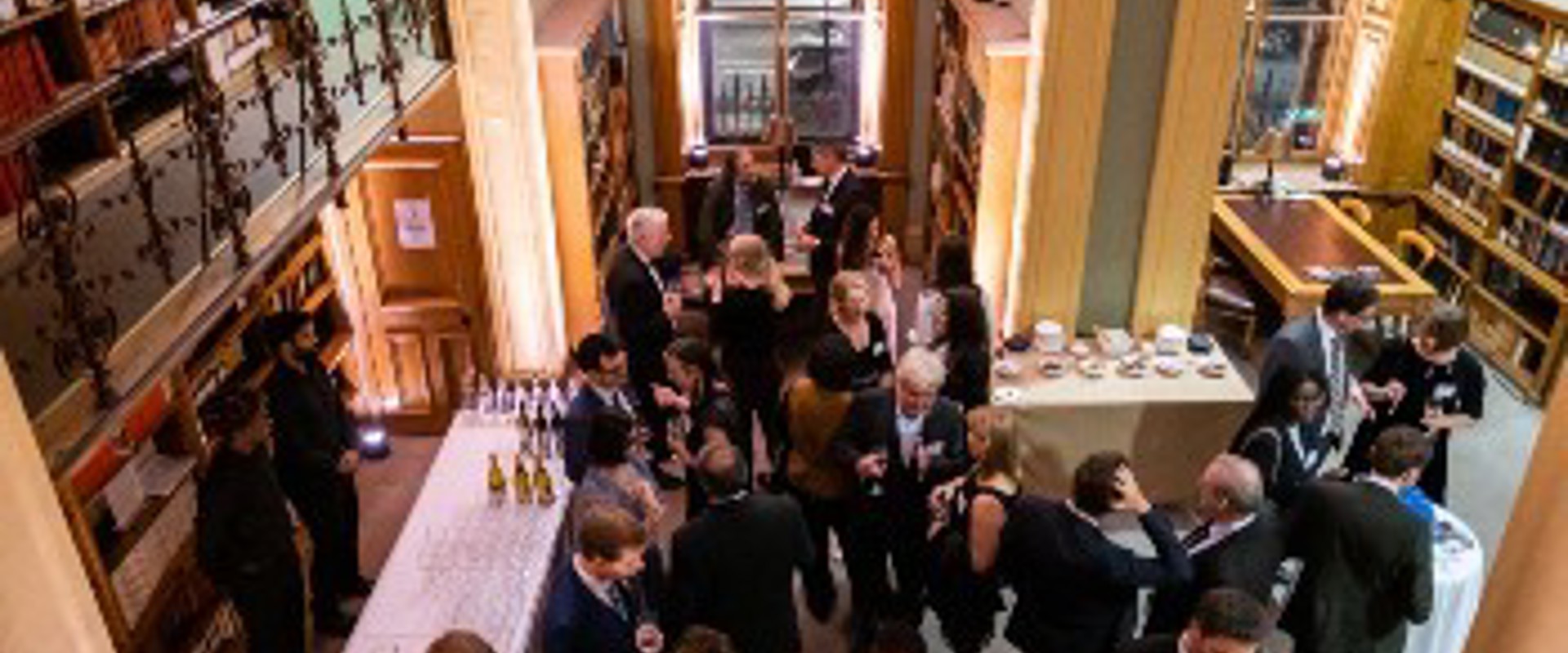 Several people standing together in a library, surrounded by books, discussing and sharing ideas.