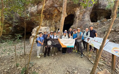 group of people standing outside a mine entrance and holding a banner reading The Geological Society