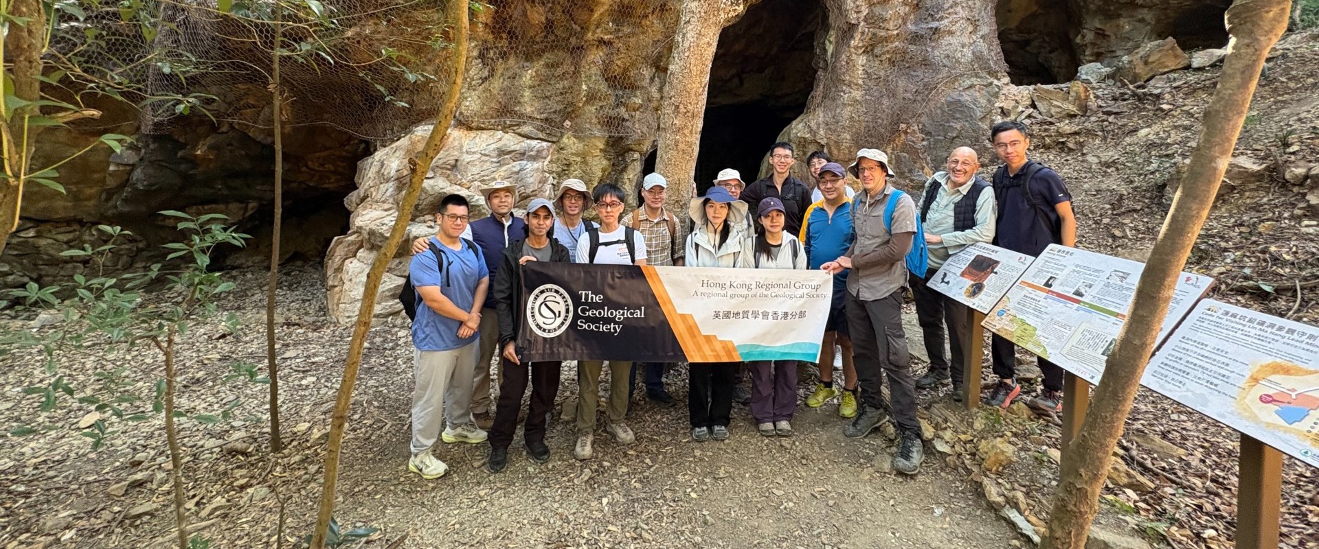 group of people standing outside a mine entrance and holding a banner reading The Geological Society