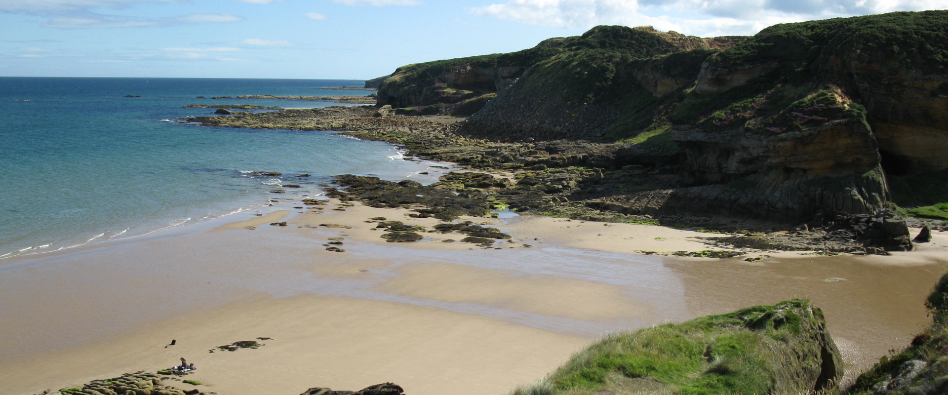 sandy beach and sloping rocks into the sea