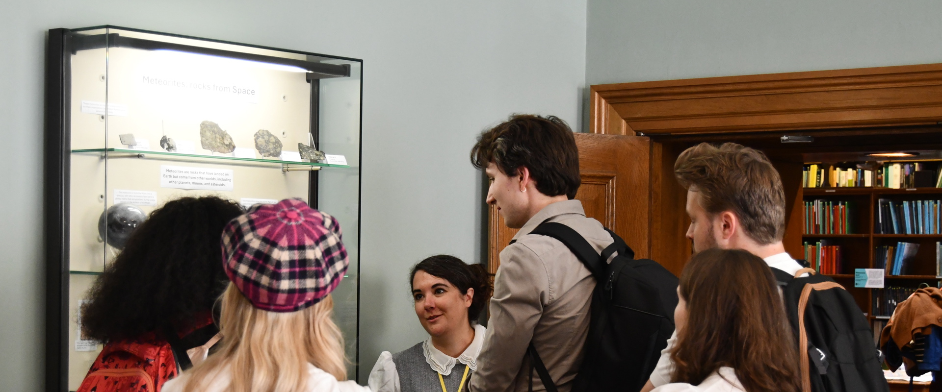 a group of people looking at a glass case of rocks which is mounted on a wall
