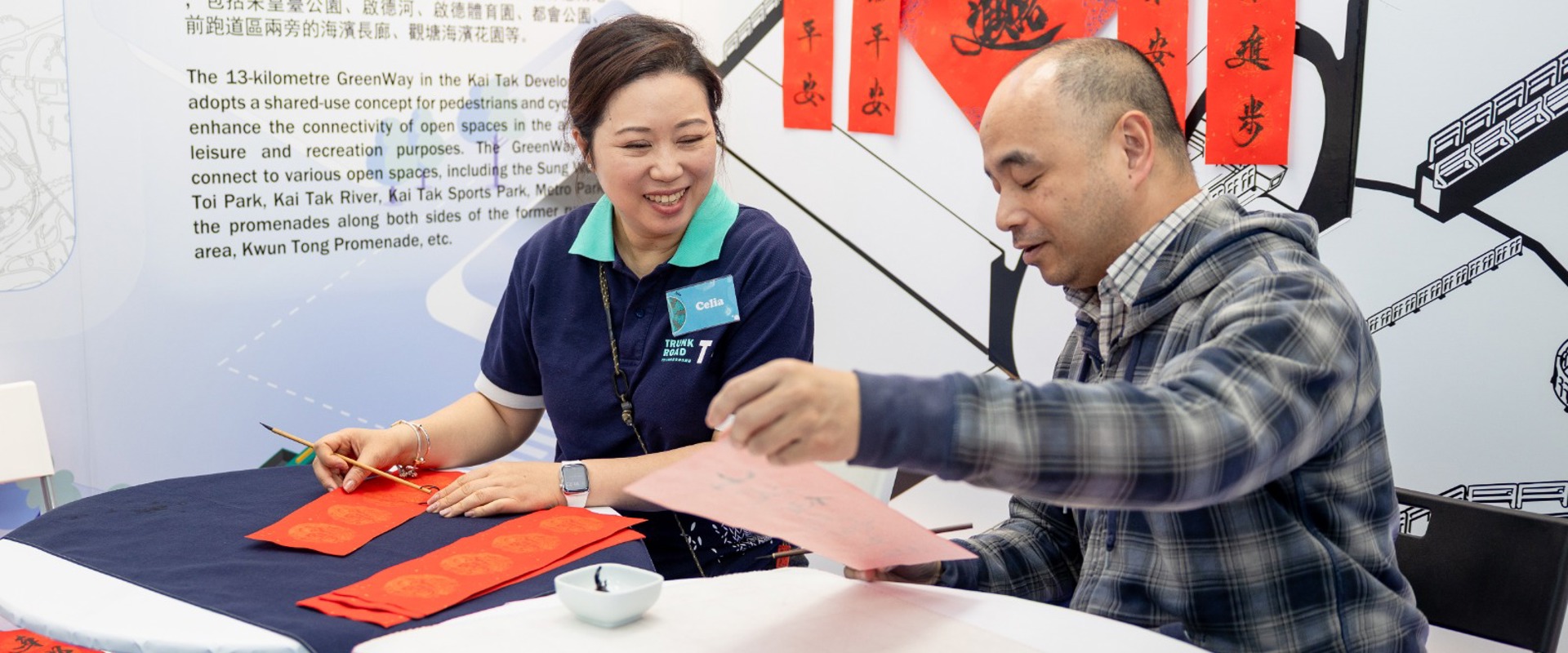 A man and a woman interacting with orange painted prints