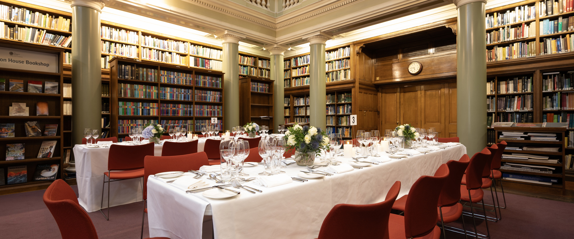 Long table sit-down dining setup in the Upper Library with a floral centrepiece and table cutlery.