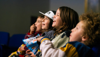Young children laughing together and eating popcorn