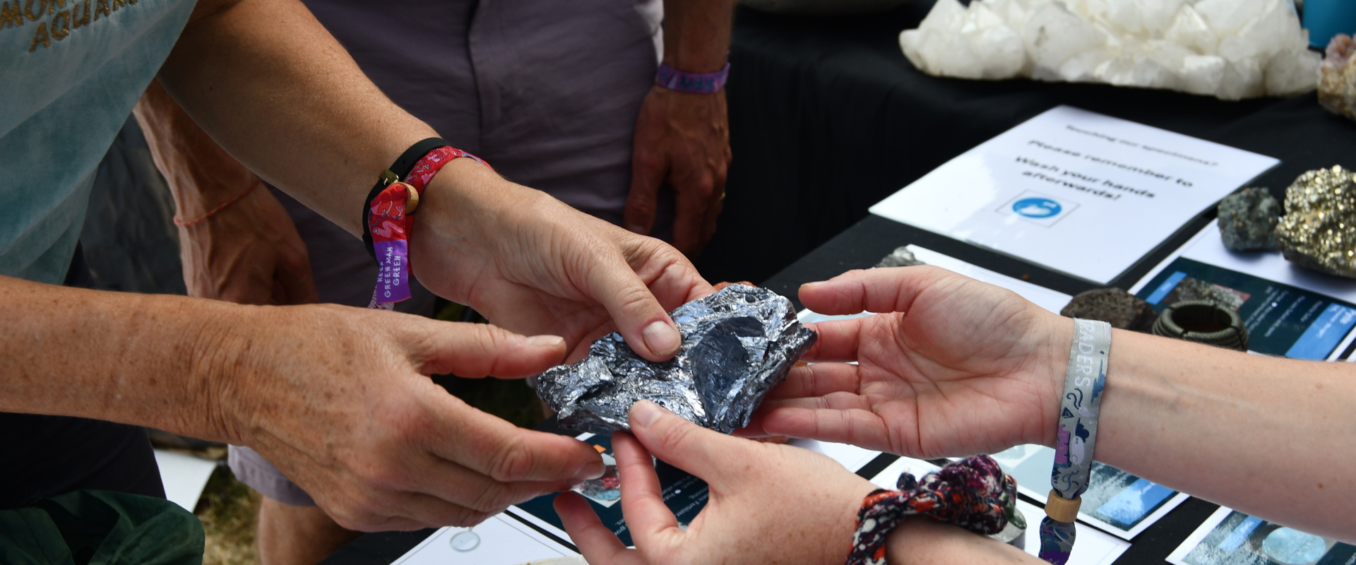 Two pairs of hands holding a rock over a table with labelled cards 