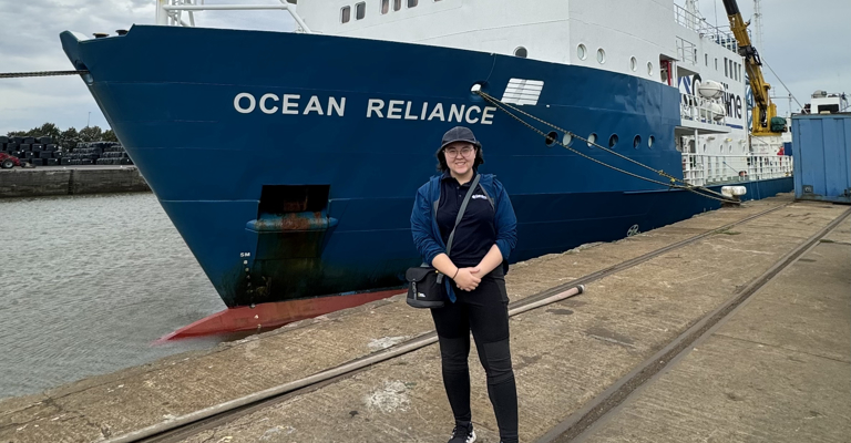 white woman standing in front of a large boat
