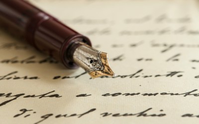 A sheet of paper with black handwriting on which rests the nib and first half of a brown fountain pen