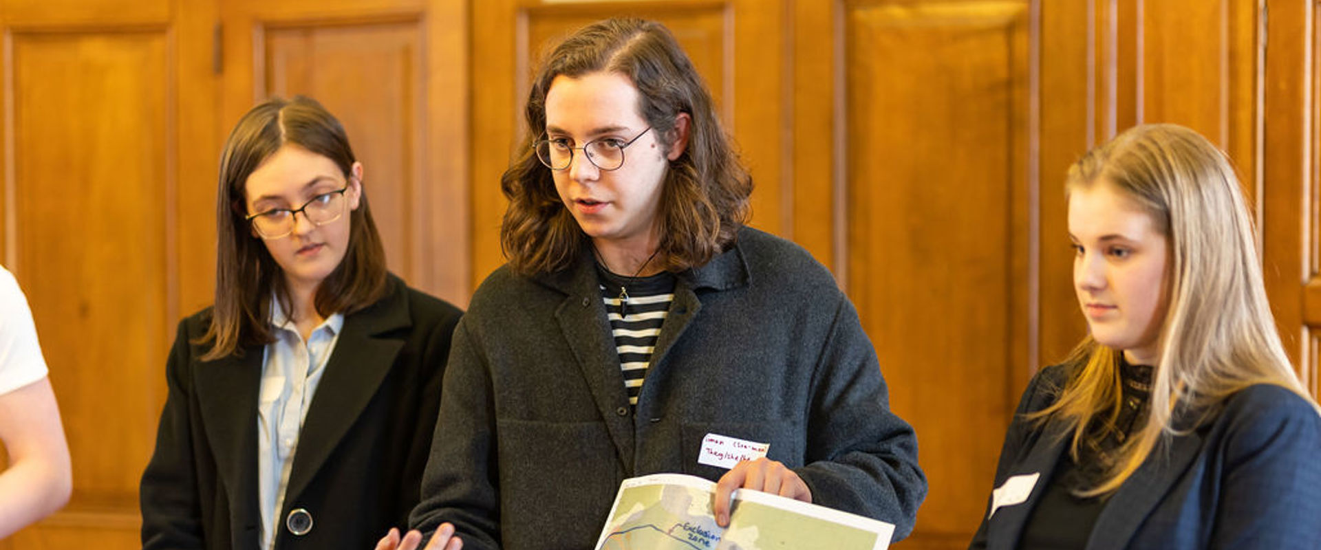 Three secondary students presenting while holding a map