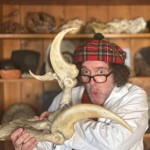 Professor Flint wearing a tartan hat and holding a dinosaur bone