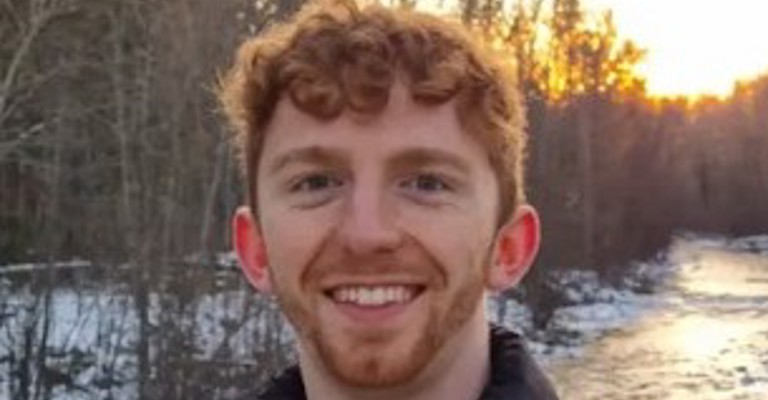 young white man with curly short red hair wearing a black north face jacket