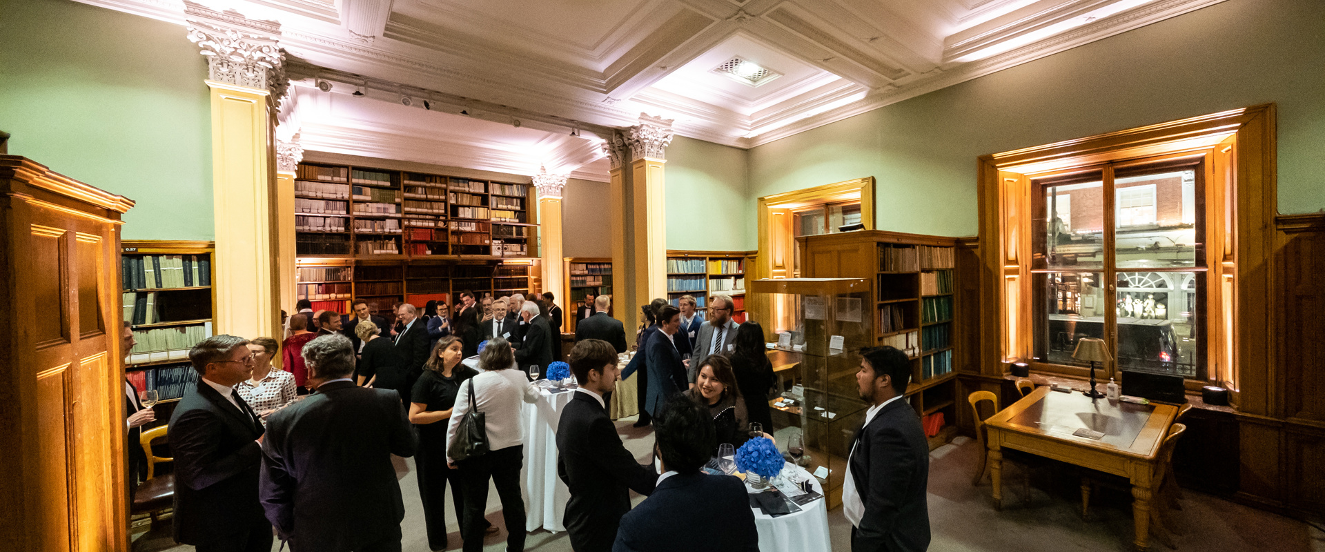 people standing at an event being held in a wood panelled library space