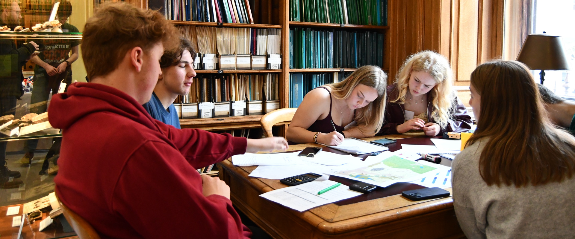 young males and females sitting at a table working on papers