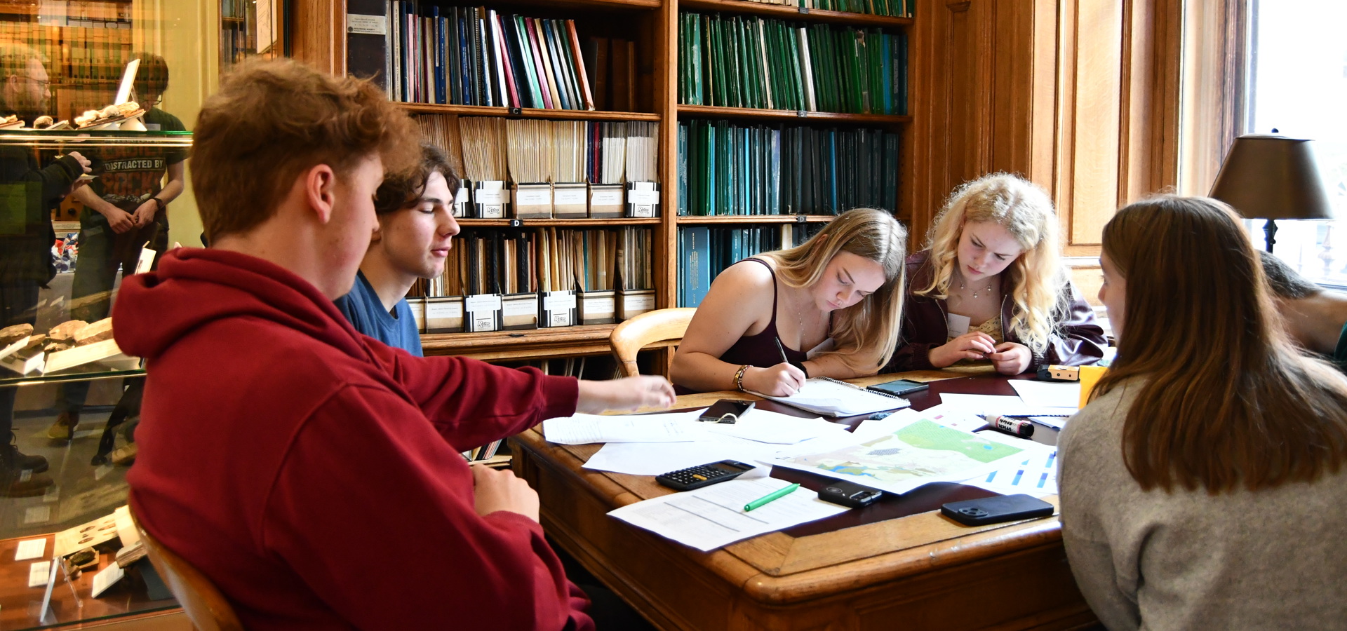 young males and females sitting at a table working on papers