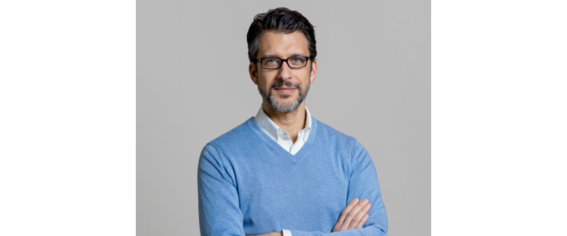  You said: alt text Copilot said: Person wearing glasses, a light blue sweater, and a white collared shirt, standing with arms crossed against a plain gray background.