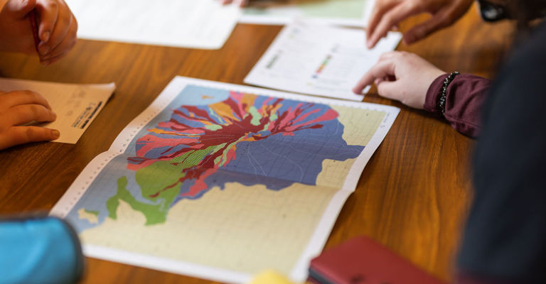Close up from a geological map on a table with hands around. 
