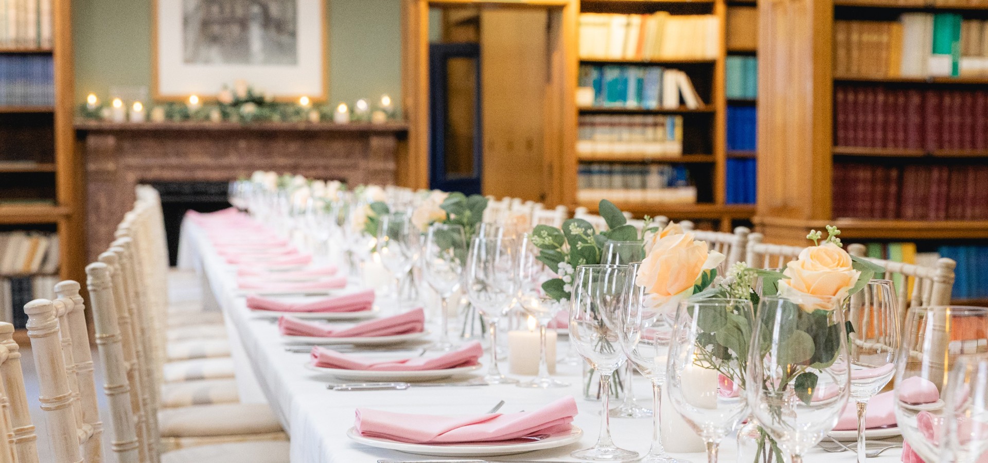shelves full of books in the background and a beautifully set table in the foreground for a wedding celebration with yellow roses in vases