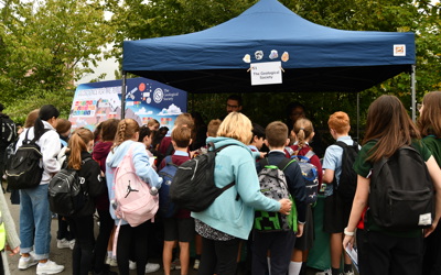 a group of young children, some in school uniform, looking at  a market stall with the geological society written above it