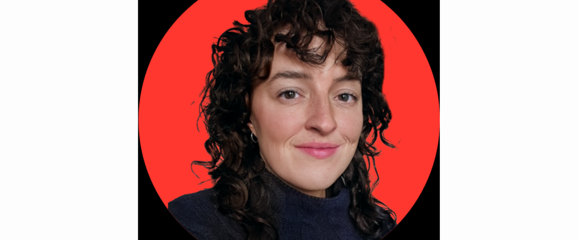 Close-up headshot of a person with short, curly dark hair wearing a dark top, centered inside a bright red circular background on a black backdrop.