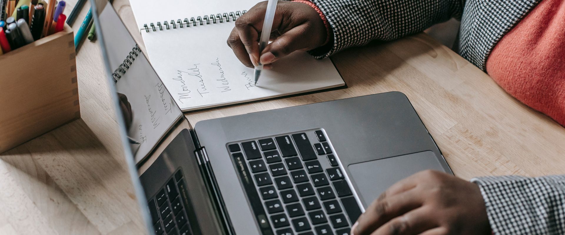 Person taking an online course and writing down notes on a notebook