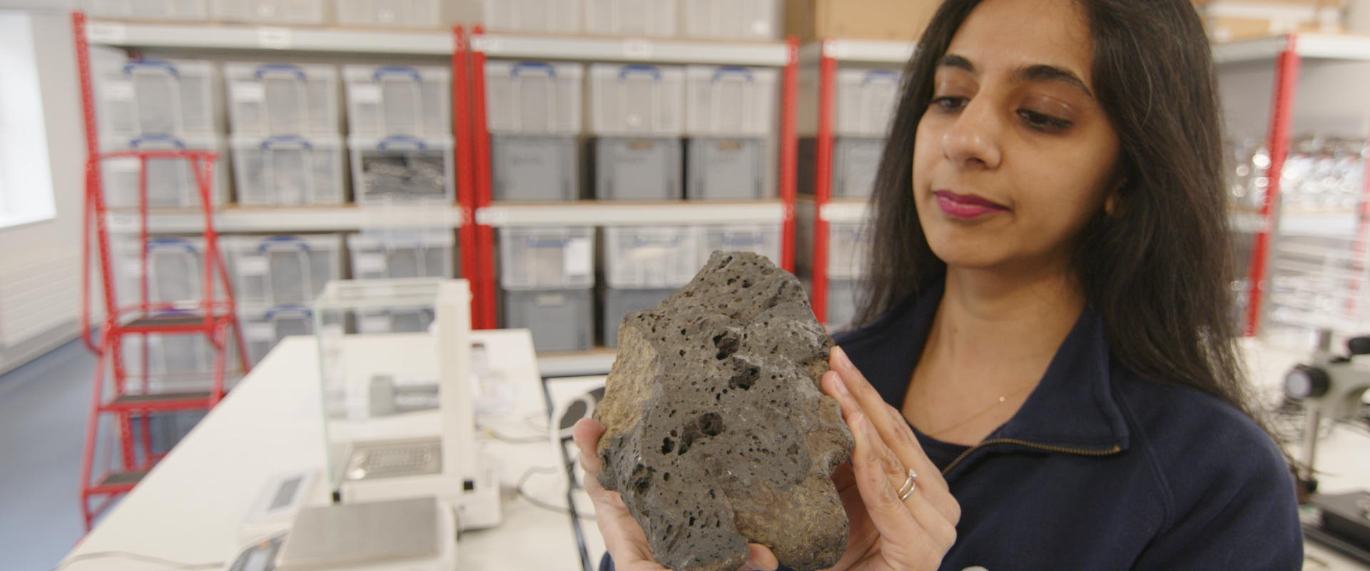 Planetary scientist holding a rock in a laboratory